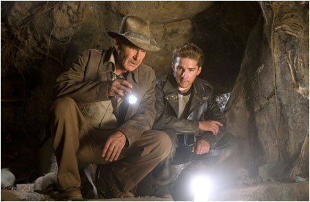 Why is Indy shining a flashlight on another light?