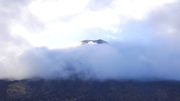 Starting out on the Tongariro Alpine Crossing with heavy winds blowing the clouds quickly through the mountaintops. It's going to be a long day.